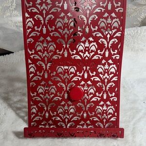 red metal cookbook stand with an intricate "Jali" (lattice) cutout design.